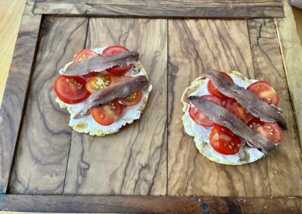 Tosta de anchoas sobre tortitas de maíz. Con queso crema y tomates cherry
