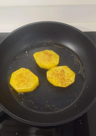 Rodajas de patata dorándose en la sartén