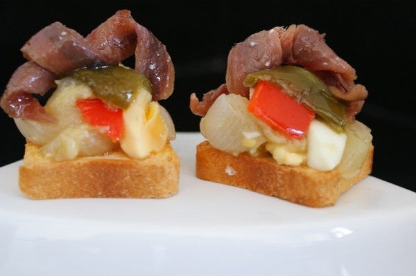 Preparación de canapé de escalibada con anchoas del Cantábrico de Conservas Serrats